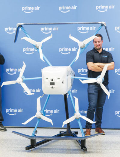  Kyle Degiulio, manager of economic development policy at Amazon, demonstrates how the drone carries the packages.  