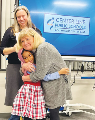  During the Nov. 24 Board of Education meeting, Peck Elementary School student Nabiha Ahmed gets a hug from teacher Judy Chapman as Peck Principal Meghan Evoy looks on.  