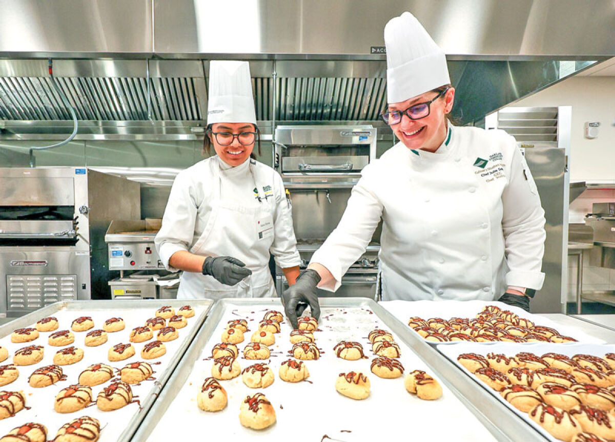  Julie Selonke, right, a professional chef and graduate of the Culinary Studies Institute at Oakland Community College, shares a moment with a student. “I fell in love with teaching as much as I fell in love with food,” Selonke said. 