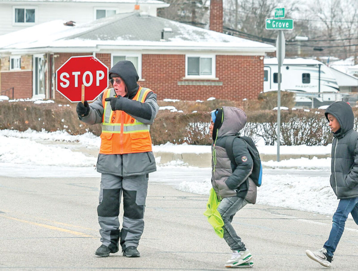  Dan Zander crosses Bellview Elementary School students at the intersection of Stephens Road and Grove Avenue, which has been his most recent post. The longtime Eastpointe Community Schools crossing guard will retire Dec. 19. He has worked for the district since 1992. 