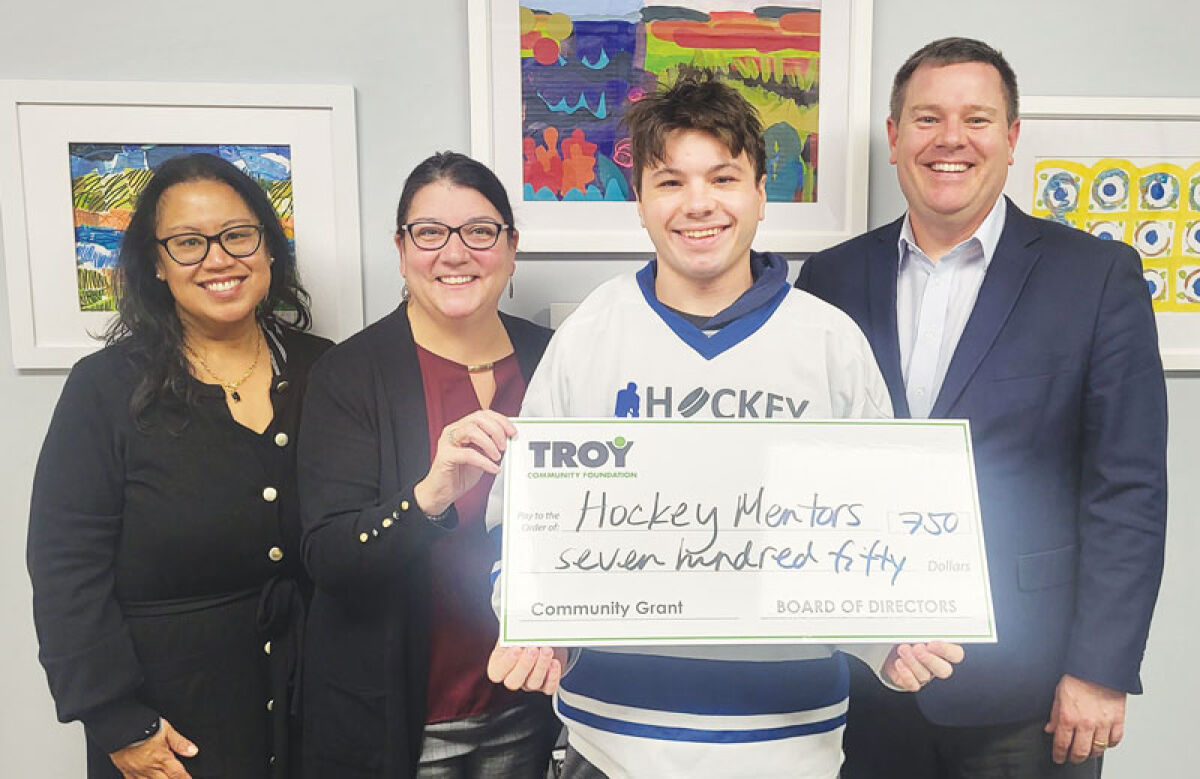  Wyatt Lucas, founder of Hockey Mentors, second from right, receives a grant for his group from the Troy Community Foundation. With him are TCF Executive Director Olivia McLaughlin, far left, and TCF Board Chair Karen Greenwood, second from left, as well as Doug Tietz, a TCF board member, right. A dozen groups received grants for their efforts. 