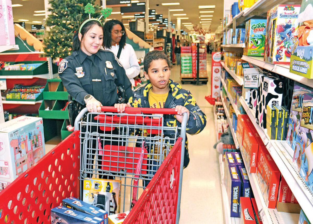  Sebastian Milano, 9, walks through the board game aisle in the Target toy department as Southfield Police Detective Alexandra Iavasile and his mother, Ashley Milano, accompany him during Heroes and Helpers Dec. 11. 