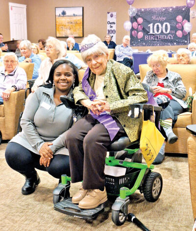  Kay Wilson wears a tiara and a sash commemorating her 100th birthday as she poses for a picture with Monique Furniss, director of life enrichment at Rose Senior Living Providence Park in Novi. 
