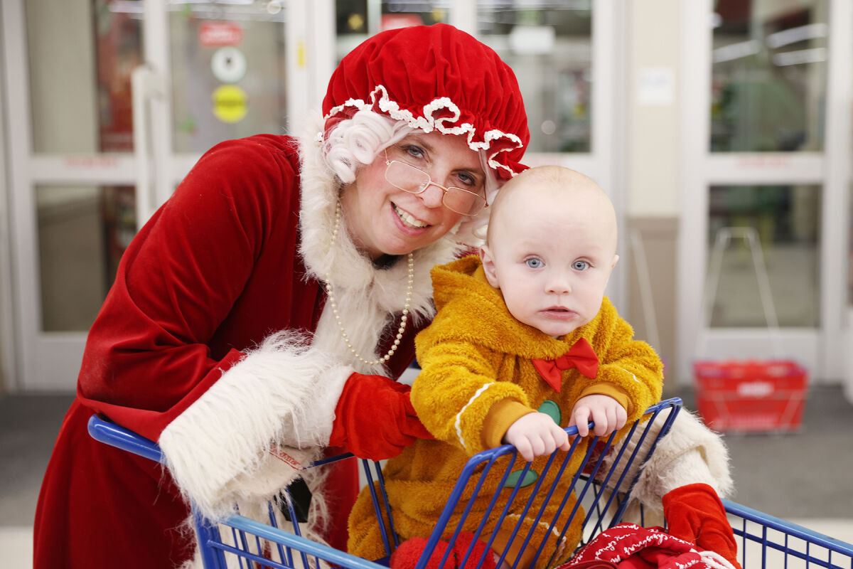  Mason Sparkman, 1, of Center Line, looking like a gingerbread man, poses with Donna Chapman, who is playing Mrs. Claus at the Shop With a Hero event.  