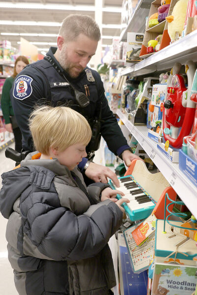  Caleb George, 7, of Royal Oak, stops to play the piano with Ferndale police officer Kevin Jerome.  