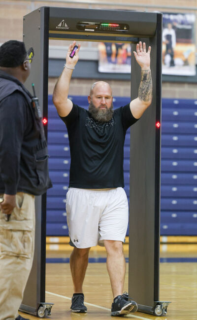  Southfield High School for the Arts & Technology health and physical education teacher Christopher Kreger walks through the metal detector with a vape pen held above his head on Dec. 17. He demonstrates for students how the metal detectors work. 