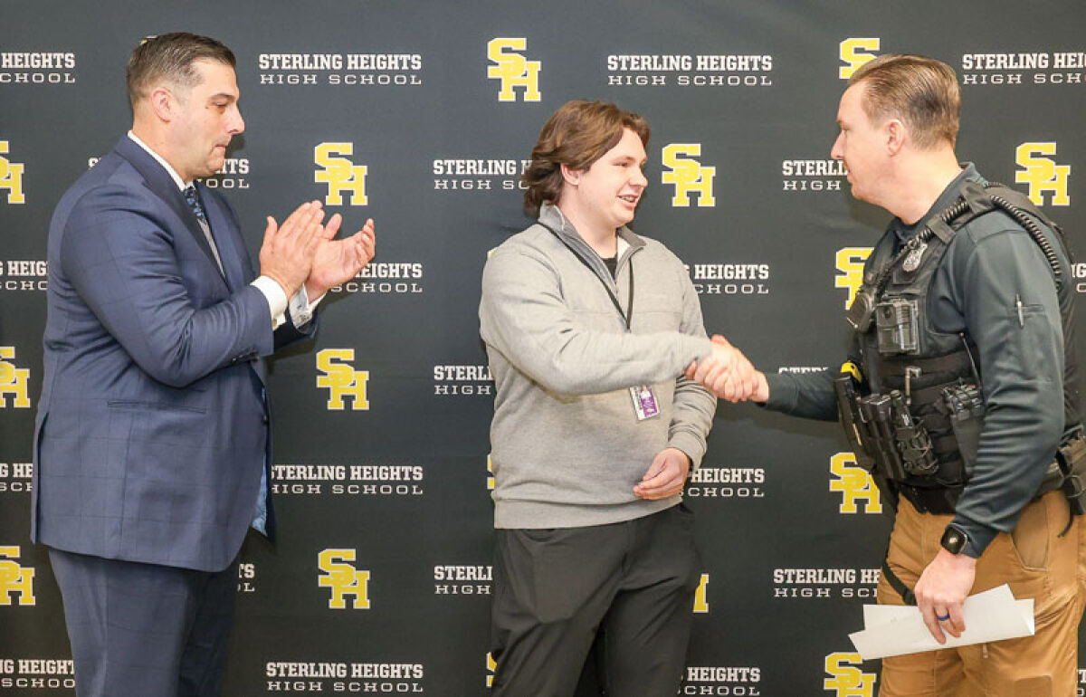  Sterling Heights High School junior Kyle Bailey, center, received a challenge coin  Dec. 18 from the high school’s resource officer Duane Casbar, right, as Warren Consolidated Schools Superintendent John Bernia looked on, left.  