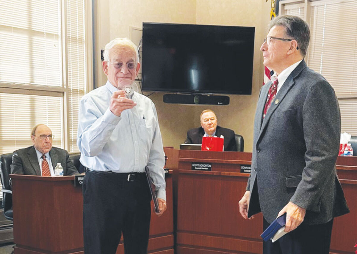  Former Grosse Pointe Shores City Councilman Robert Barrette looks at the crystal etched with the city’s logo that he received from Mayor Ted Kedzierski during a Dec. 16 City Council meeting. 